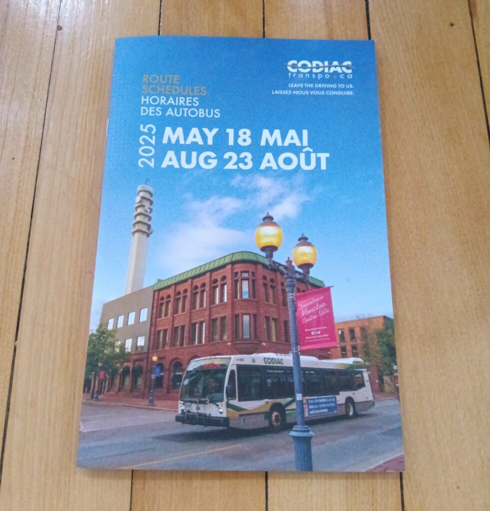 A Codiac Transpo route schedule for summer 2025 sits on wooden floorboards.
