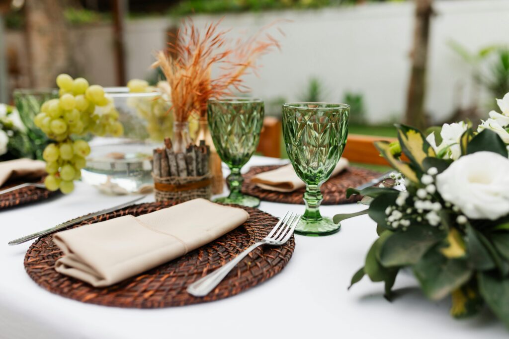Table settings featuring green glass goblets and white flowers.