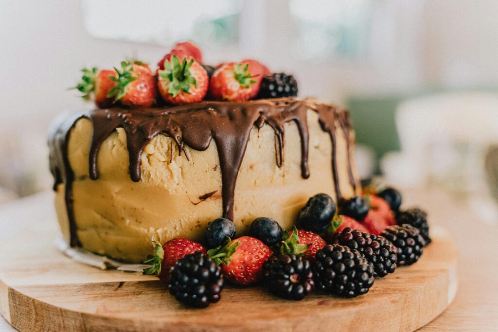A creamy cake with a chocolate glaze topped with berries.