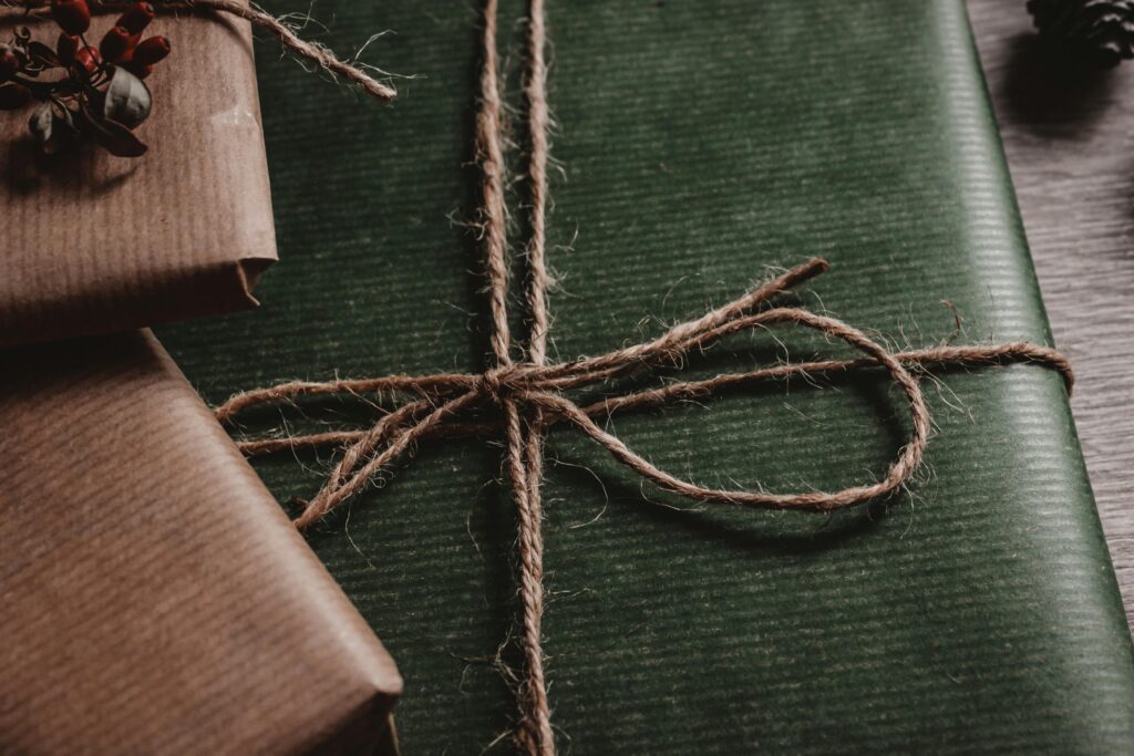 A stack of presents wrapped in green and brown paper tied up with string.