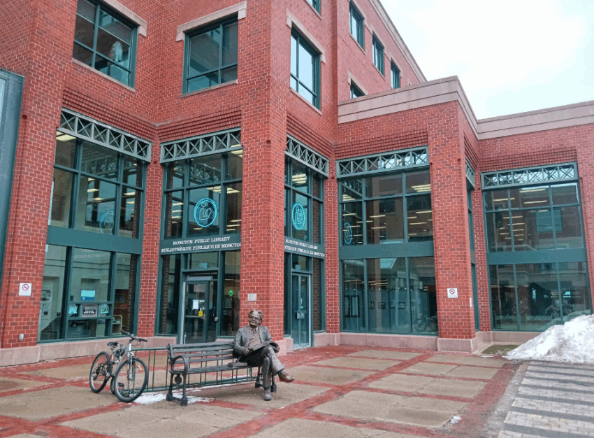 A brick library building with a bench out front.