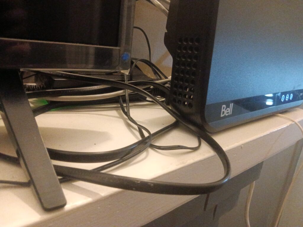 A set of cables next to a Bell wifi modem and television.