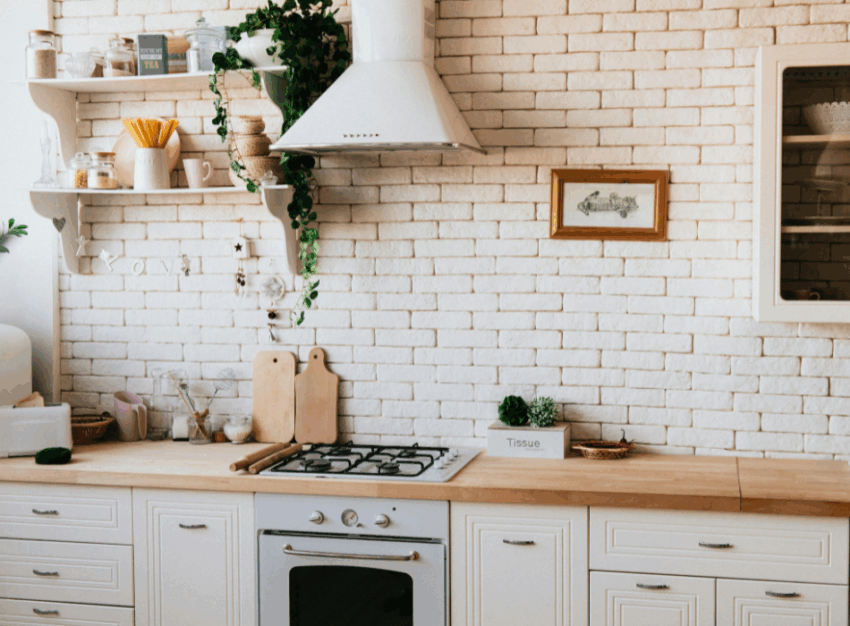 A white kitchen featuring drawers, a wooden counter and shelves with pantry items.