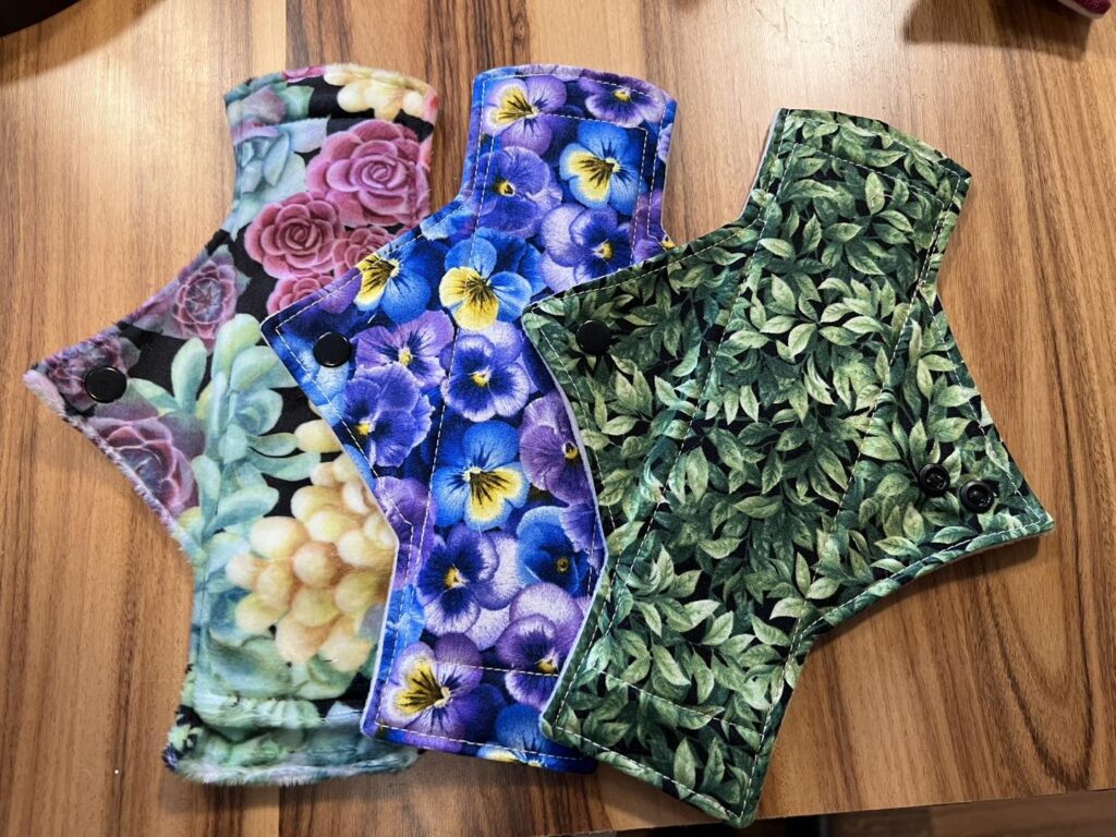 Three reusable cloth pads with colourful patterns.