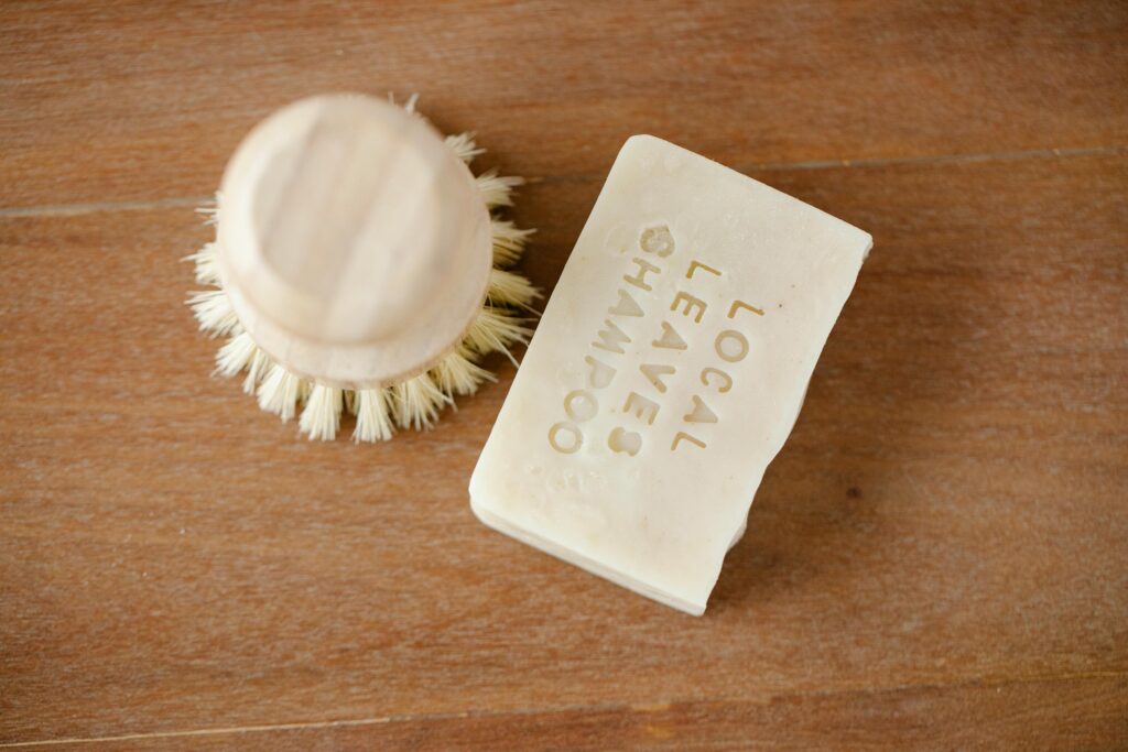 A creamy shampoo bar sits next to a small wooden brush.