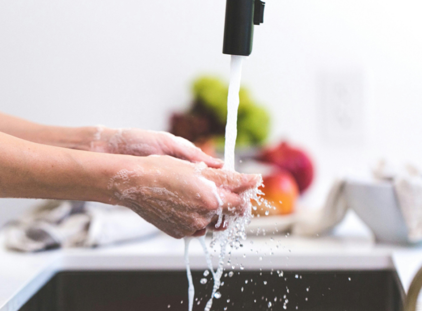 A person washes their hands under a running tap.