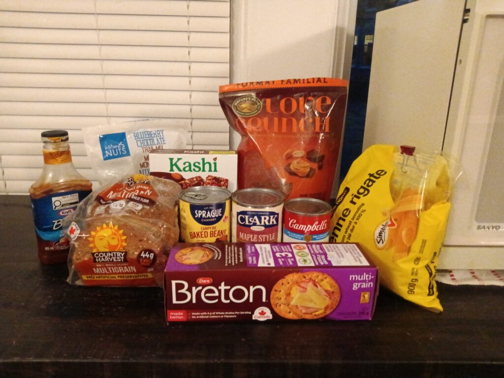 An assortment of packaged foods, including crackers, bread, baked beans, pasta and cereal.